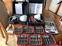 Overview of two paint sprayers in cases and drill bit sets on table, showing condition and scale