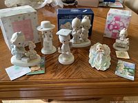 Full view of all seven Precious Moments figurines displayed on table, with three original boxes in background