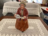 Front view of Royal Doulton 'Teatime' figurine showing woman pouring tea from a teapot into a teacup, set against a lace-covered table.
