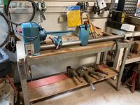 Full view of Ryobi WL-37 lathe mounted on metal stand with wood shelf and accessories below