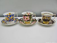 Three Royal Albert bone china cups and saucers displayed side by side showing pattern colors and designs