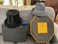 Black Woodrow & Son top hat and grey felt Borsalino hat with Dobbs Fifth Avenue box and brush, displayed on a sofa.