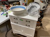 Side angle showing large vintage washbowl with blue rim and enamelled urinal on washstand surface.