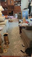 View of light gray area rug with branch and leaf pattern partially under furniture including couches, tables, and decor items.