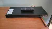 Sony BlueRay player with remote placed on a wooden surface, showing top view and the overall appearance.