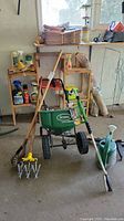 Scotts Speed Green 1000 seed spreader with green hopper, wooden handled garden tool, and watering can in background.