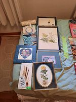 Wide view showing six framed floral prints and one Welcome wooden sign on table with other items