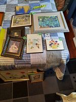 Overview of all prints including framed floral, bird, portrait, and unframed prints on a bed and floor