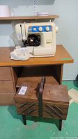Full view of cream colored Brother VX-1140 sewing machine on wood shelf with detached accessory tray and vintage wooden sewing box with metal hinges and handle placed below shelf