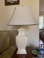 Taller cream ceramic lamp with urn-shaped base and bell-shaped fabric shade.