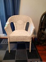 Front view of white wicker armchair showing design and condition.
