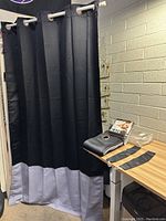 Curtains hanging from a rod showing full length and grommets for hanging. Included are accessories on the table beside the curtains.