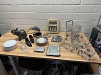 Overall view of assorted decorative and household items on a wooden desk, including photo frames, wire baskets, figurines, and small collectibles.