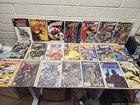 Full overview of lot of 19 comics spread on table in three rows, showing various superhero titles.
