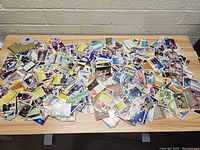 Photo showing an extensive scatter of sports cards spread out on a table including baseball and basketball cards in colorful designs.