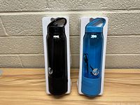 Front view of two water bottles, one black and one blue, each with integrated Bluetooth speaker bases.
