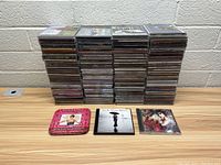 Four stacks of CDs with three CDs laid out in front, showing various genres and artists.