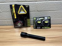 Photo showing all items together: Glow Max packaged items and loose black flashlight on table against wall.
