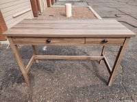 Front view of the wooden desk showing two drawers with black knobs and four legs.