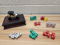Wide view of entire lot showing wooden playing card case with Model T car figurine and multiple sets of dice in different colors and types.