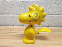 Front side view of yellow Woodstock figurine showing speaker area on head and mouth smile