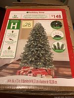 Front of the original box packaging showing image of the assembled tree decorated with white LED lights, brand Holiday Time, specifications such as 6ft height and 38 inch diameter base.