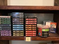 Cassette tapes and DVD blank discs on a wooden shelf, showing various classical music titles and the DVD spindle pack