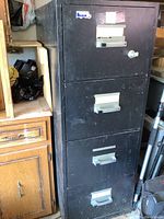 Front view of black three-drawer filing cabinet showing metal handles and lock on top drawer