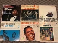 Collection of six Louis Armstrong and related jazz artist vinyl album covers shown laid out on a surface.