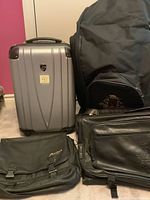 Silver hardcase suitcase, black garment bag, and two black bags including a golf bag and a messenger bag