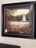 Front view of framed boat wall art depicting a sailboat and small rowboat on a lake.
