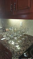 Image showing a collection of various wine and cognac glasses arranged on kitchen countertop.