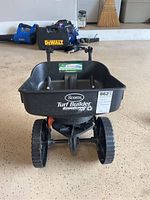 Front view of Scotts Turf Builder EdgeGuard Mini broadcast spreader showing large wheels and hopper with label.