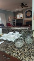 Four square white ceramic bowls each placed on matching square plates, all on a large rectangular white ceramic serving platter, set on granite counter