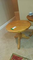 Photo showing sidewood round side table with scalloped edge top and pedestal base with three legs.