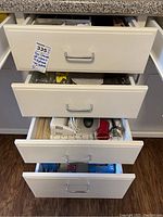 Six kitchen drawers pictured open showing contents of flatware, utensils, and kitchen gadgets