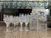 Wide shot showing four decanters with stoppers and grouped glassware on counter, viewed near mirror with reflection