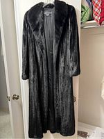 Front view of full-length black mink fur coat on hanger