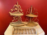 Lot overview showing two wicker corner shelves and a wicker bamboo towel rack on a light surface against red wall.