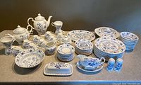 Overview of entire 77-piece dinnerware set including plates, bowls, cups, saucers and serveware pieces.