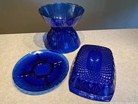 Front angle showing all three cobalt blue glass serving pieces with detailed embossed patterns
