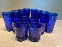 Front view of 14 cobalt blue glasses arranged in rows showing two different sizes