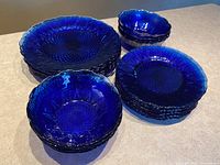 Group display of stacked dinner plates, salad bowls and dessert plates on countertop.