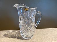 Clear crystal pitcher jug with etched pinwheel and starburst patterns and original Zajecar tag visible on the front.