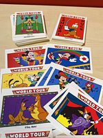 Two stacks of World Tour Disney trading cards plus loose cards spread on a table, showing cartoon scenes featuring Disney characters in various themed environments.