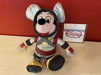 Front view of Mickey Mouse astronaut plush with Disney Store tag visible in background.