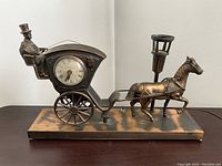 Left side view of metal horse carriage lamp with clock and rider in top hat, horse and lamp post on base
