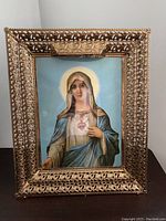 Full view of the Lady of Grace framed artwork showing detailed metal ornate frame and painted image of Mary with halo and blue robe.