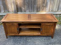 Front view of the wooden coffee table showing two cupboard doors and open center shelf.