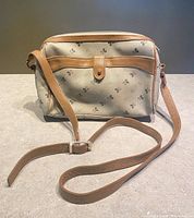 Full view of vintage Mickey Mouse shoulder bag made of beige fabric with dark Mickey Mouse heads print and tan leather strap and trim, adjustable shoulder strap in tan leather.